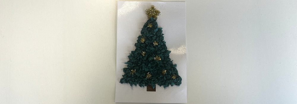 Handgjord julgransdekoration av grön silkespapper med guldtinsel och brun pappersstam